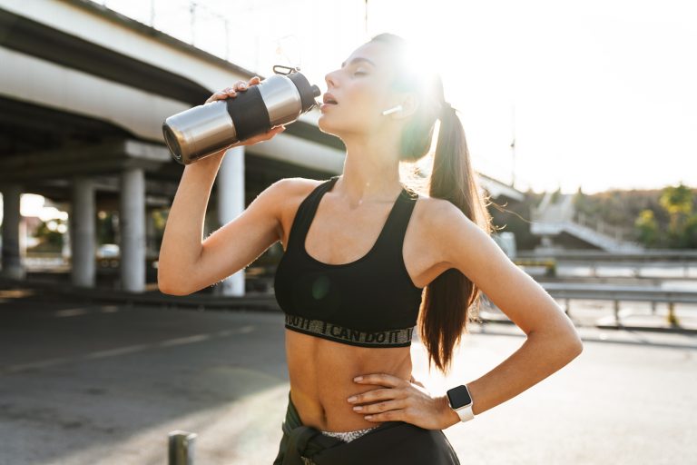 Sports fitness woman outdoors drinking water.